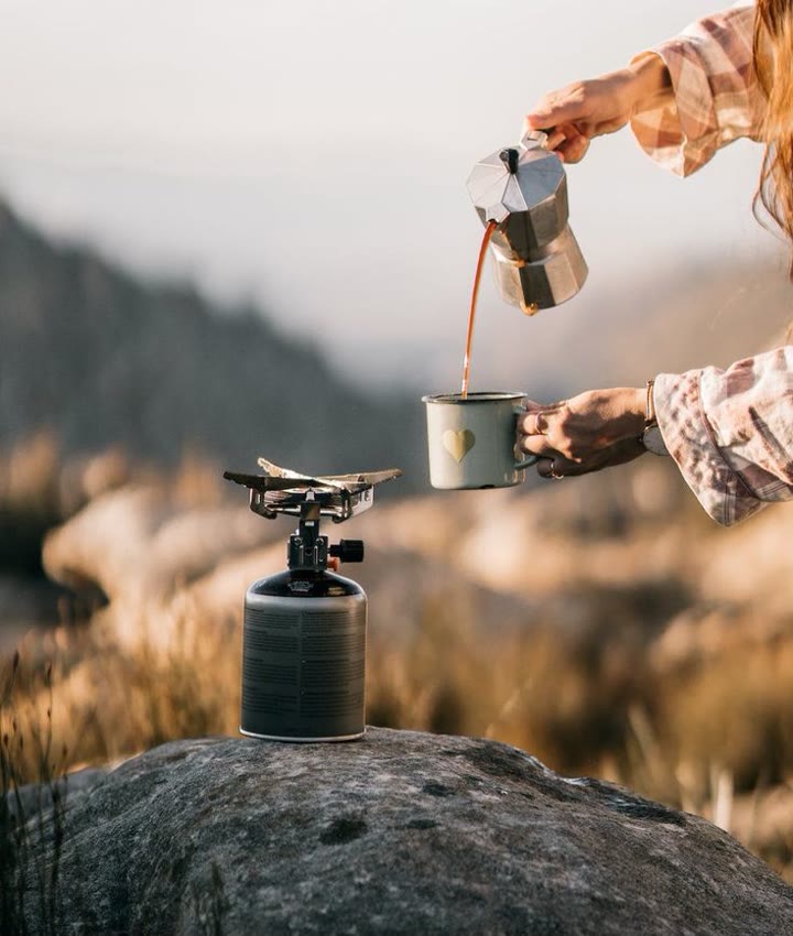 Outdoor coffee poured beside a camp stove