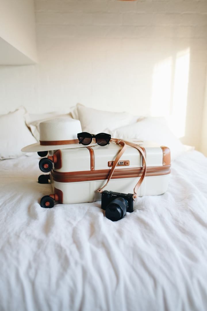Styled luggage and camera on a bright hotel bed